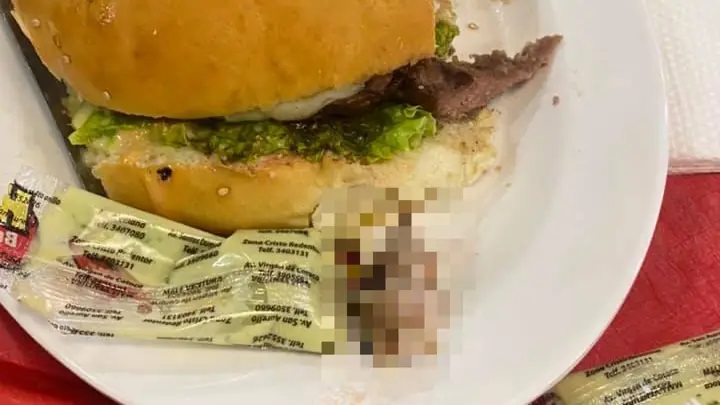 امرأة تتعرض لكارثة أثناء عض "ساندويتش هامبرغر" في مطعم للوجبات السريعة